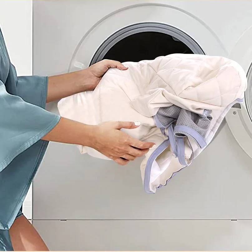The bed's zipped cover being put into a washing machine