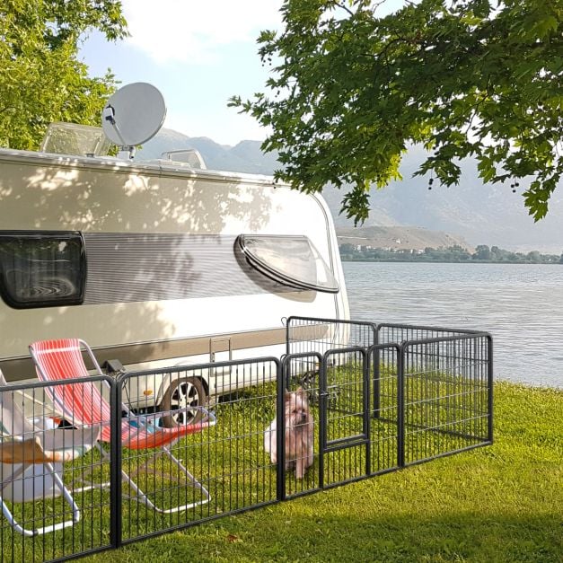 Black metal pet playpen beside a caravan